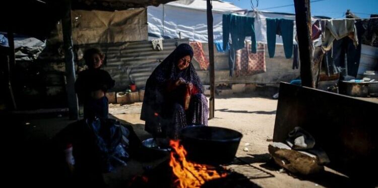 غزہ میں گیس بحران کے باعث کچرے سے آگ جلاتی فلسطینی خاتون اور صحت کے خطرات